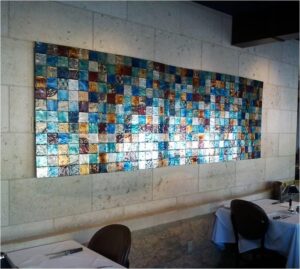 colorful tiled art piece installed on a tiled concrete wall
